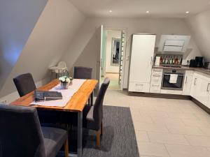 a dining room with a table and chairs and a kitchen at Ferienwohnung Brigitta in Hambühren