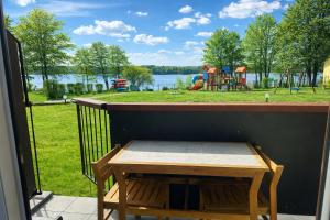 a table on a balcony with a view of a playground at KAMERALNY przy promenadzie - pokoje in Charzykowy