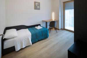 a bedroom with a bed and a table with a window at - Magenta Apartment - in Monfalcone