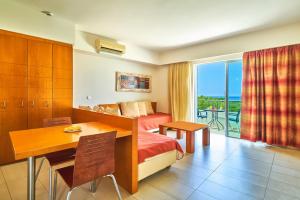 a hotel room with a bed and a desk and a table at Bella Pais in Maleme