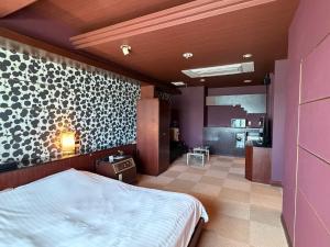 a bedroom with a white bed and a kitchen at HOTEL AMARIS & HIP (Adult Only) in Kanazawa