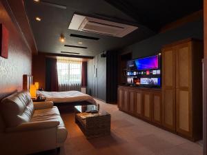 a living room with a couch and a television at HOTEL AMARIS & HIP (Adult Only) in Kanazawa