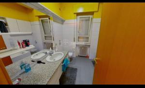a bathroom with two sinks and a yellow wall at private room in Seveso