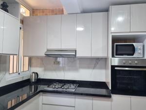 a kitchen with white cabinets and a stove top oven at Appartement Imi-Ouaddar 2 in Agadir nʼ Aït Sa +8 photos