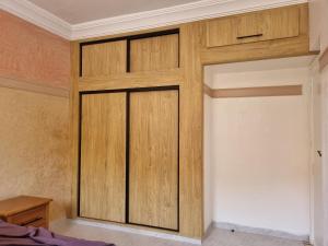 a closet with wooden doors in a bedroom at Appartement Imi-Ouaddar 2 in Agadir nʼ Aït Sa
