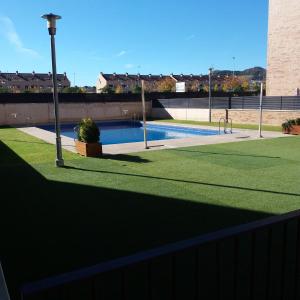 a swimming pool with green grass next to a fence at Poesia y Vino in Lardero