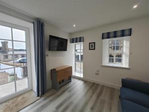 a living room with a couch and a tv and windows at 1 Bed in Isle Of Arran oc-96463 in Dougarie