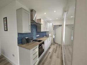 a kitchen with white cabinets and blue tiles on the wall at 1 Bed in Isle Of Arran oc-96463 in Dougarie
