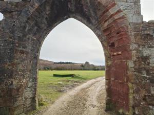 an archway in an old brick wall with a dirt road at 1 Bed in Isle Of Arran oc-96463 in Dougarie