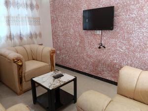 a living room with two chairs and a flat screen tv at Guest House ETE-D Plus in Bohicon