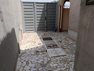 a walkway with a gate and a tile floor at Guest House ETE-D Plus in Bohicon