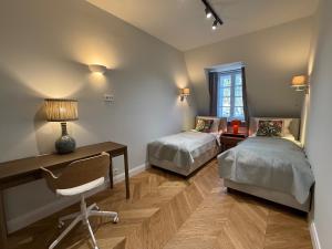 a bedroom with two beds and a desk and a chair at Apartament Kirkor przy Dworku Bielin in Bielin