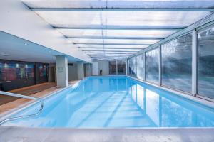an indoor swimming pool with blue water and windows at Fletcher Resort-Hotel Zutphen in Zutphen