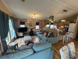 a living room with two blue couches and a kitchen at Luxury Lakeside Lodge L1 with hot tub situated at Tattershall Lakes Country Park in Tattershall
