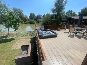 a wooden deck with a bed on top of it at Luxury Lakeside Lodge L1 with hot tub situated at Tattershall Lakes Country Park in Tattershall
