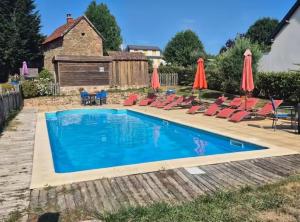 a swimming pool with chairs and umbrellas at Gîte Léon, Beynat, Corrèze in Beynat