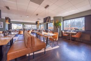 a restaurant with tables and chairs and windows at Fletcher Resort-Hotel Zutphen in Zutphen