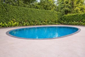 a swimming pool in a garden with a hedge at Tivoli Bijwasan in Jāmb