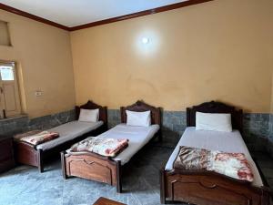 a room with two beds and two ottomans at Qaiser Hotel in Lahore