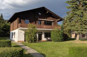 a wooden house with a balcony on top of a yard at Ferienwohnung am Badesee in Arrach