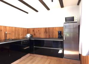 a kitchen with black cabinets and a stainless steel refrigerator at Ferienwohnung am Badesee in Arrach