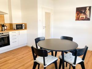 a dining room table with four chairs and a kitchen at Modern Apartment Wissenbach 1 in Eschenburg +6 photos