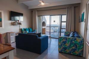 a living room with a couch and chairs and a balcony at Mitford-on-Sea in Morganʼs Bay