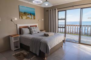 a bedroom with a bed with a view of the ocean at Mitford-on-Sea in Morganʼs Bay