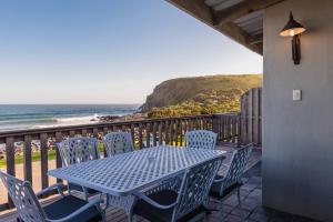 a blue table and chairs on a balcony with the ocean at Mitford-on-Sea in Morganʼs Bay