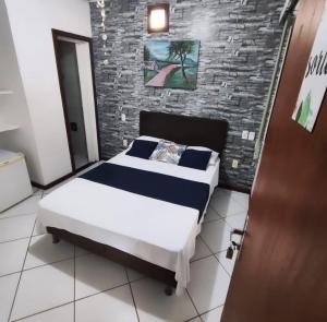 a bedroom with a bed and a brick wall at pousada peracanga in Guarapari