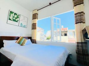 a bedroom with a bed and a large window at holtel Tâm An in Da Lat