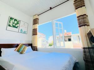 a bedroom with a bed and a large window at holtel Tâm An in Da Lat