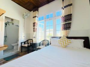 a bedroom with a white bed with a large window at holtel Tâm An in Da Lat