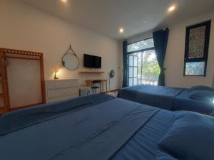 a bedroom with two beds and a tv and a window at H2B Homestay Mountains view near Bai Dai Beach in Cam Lâm