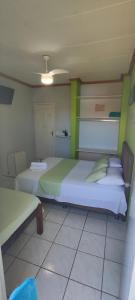 a bedroom with a large white bed with green accents at pousada peracanga in Guarapari