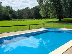 a blue swimming pool with a field in the background at Posada Quellen in Villa General Belgrano