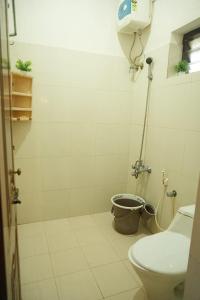 a bathroom with a shower with a toilet and a bucket at Baywatch Beach Resort in Alleppey +54 photos