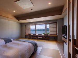 a bedroom with a bed and chairs and a television at Rako Hananoi Hotel in Suwa