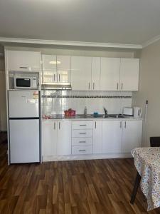 a kitchen with white cabinets and a white refrigerator at Manduhra Motel Resort in Mandurah