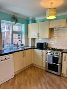 a kitchen with white cabinets and a stove top oven at Bayfields house by the Sea, parking, garden, central location in Portsmouth