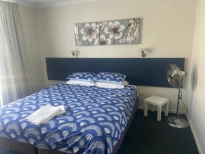 a bedroom with a blue and white bed and a fan at Manduhra Motel Resort in Mandurah