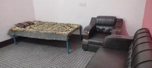 a room with a bed and a couch and a chair at Gyan Homestay in Bareilly