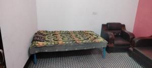 a bed in a room with a chair and a couch at Gyan Homestay in Bareilly