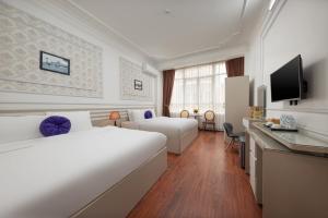 a hotel room with two beds and a television at The Lake Silk Hotel & Travel in Hanoi