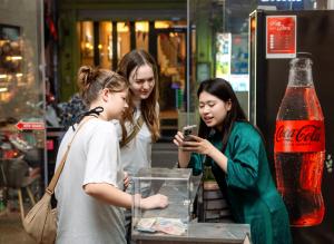 three girls looking at a cell phone in a store at The Lake Silk Hotel & Travel in Hanoi
