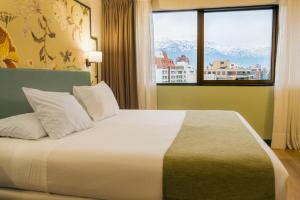 a bedroom with a large bed with a large window at Hotel Director Vitacura in Santiago
