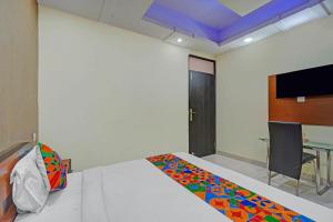 a room with a bed and a table and a tv at FabHotel HM Inn in Lucknow +24 photos