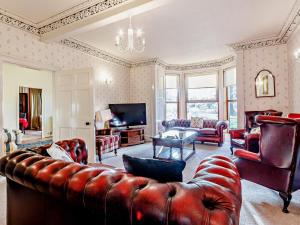 a living room with a leather couch and a television at 7 Bed in Cupar oc-81242 in Cupar