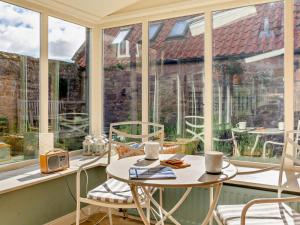 a conservatory with a table and chairs in front of a window at 4 Bed in Chathill oc-93702 in Ellingham