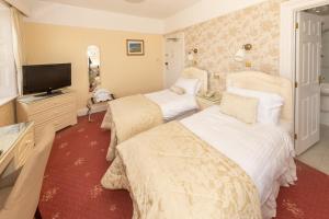 a bedroom with two beds and a flat screen tv at Haddon House Hotel in Bridport